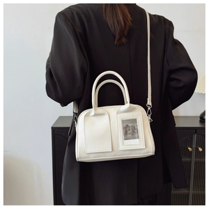 Close-up of a white shell-shaped shoulder bag featuring a unique transparent photo window