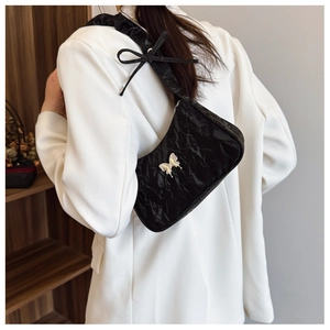 Detail of black pleated shoulder bag with silver butterfly buckle and bow strap