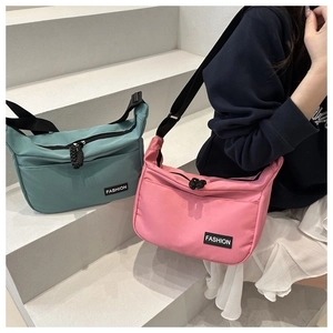 Detail of pink and cyan nylon crescent crossbody bags with adjustable straps and fashion label