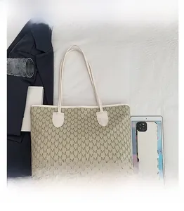 Detail view of large M-print tote bag with white handles and spacious interior layout