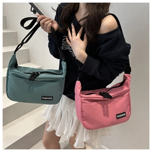 Detail of nylon crossbody bags in green and pink with adjustable straps and fashion label