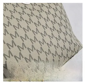 Detailed macro view of the beige tote bag featuring embossed M pattern and lychee texture