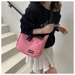 Detail of pink nylon crossbody bag with fashion label on shoulder of casual outfit