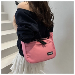 Detail of pink nylon crossbody bag featuring fashion label and black zipper closure