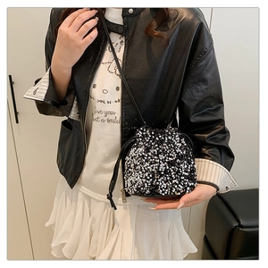 Détail d'un sac seau scintillant à paillettes noires et argentées avec fine bandoulière