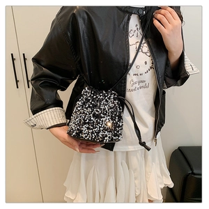 Detail of shimmering black sequins and drawstring closure on a trendy bucket bag