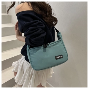 Green nylon tote bag showing adjustable black strap and fashion label detail