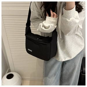 Detail of black nylon dumpling bag with adjustable strap and fashion label