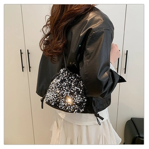Mini silver sequined drawstring bucket bag worn by model showing the strap and size
