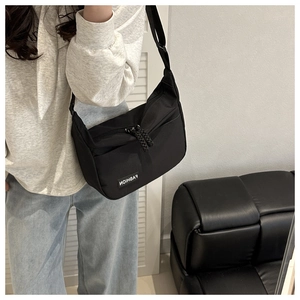 Detail of black crossbody bag featuring a durable texture and a white Fashion label tag