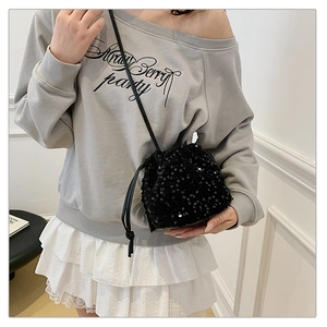 Close-up of sparkling black sequin bucket bag with drawstring and thin shoulder strap