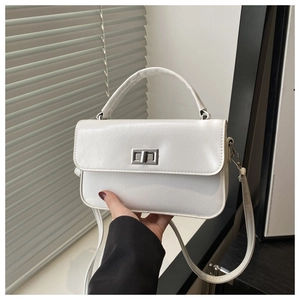 Détail du sac vintage blanc avec fermoir rotatif argenté et texture cuir fine