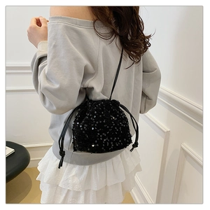 Sac seau chic à paillettes noires avec cordon de serrage, porté par un mannequin en studio