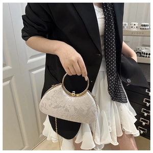 Detail of white jacquard party bag with floral texture and golden circular handle
