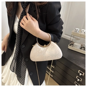 Close-up of elegant ivory white lace embroidery handbag with gold metal ring handle