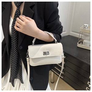 Détail d'un petit sac beige avec boucle métallique argentée et bandoulière réglable