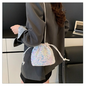 Close-up of iridescent sequin drawstring bucket bag worn over the shoulder by a model