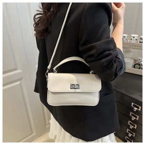 Détail d'un sac à main blanc en cuir avec fermoir rotatif argenté porté par un mannequin