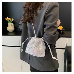 Détail du sac seau à paillettes avec cordon porté par un mannequin en blazer gris
