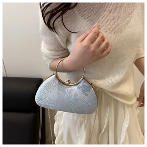 Close-up of light blue floral texture bag with a gold ring handle and bead clasp