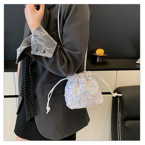 Close-up of sparkling sequin bucket bag with drawstring closure and colorful reflections