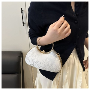 Macro shot of white floral lace fabric and golden ring handle on a shell-shaped evening bag