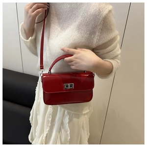 Gros plan d'un petit sac carré en cuir verni rouge avec fermoir rotatif en métal argenté