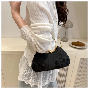 Detail of black jacquard evening bag with golden ring handle and chain strap on shoulder