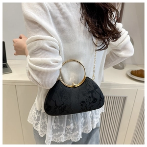Close-up of black textured fabric evening bag with round gold handle and chain strap