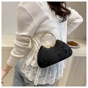 Detail of the vintage black jacquard handbag featuring a gold circular metal handle and chain