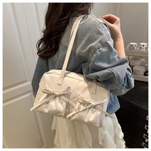 Détail du sac à bandoulière blanc crème avec deux poches plissées et nœuds élégants