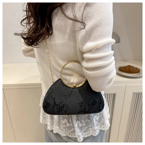 Detail of black floral jacquard evening bag with golden ring handle and chain