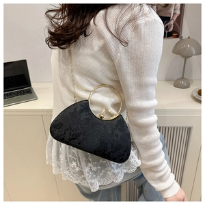 Detail view of black floral jacquard evening bag with golden ring handle and chain