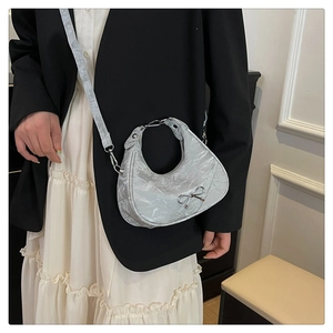 Close-up of silver bow detail on a pleated metallic shoulder bag for women