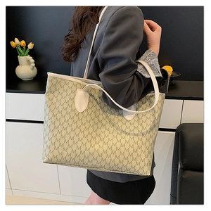 Model showing large beige tote bag with M-pattern print and white leather straps