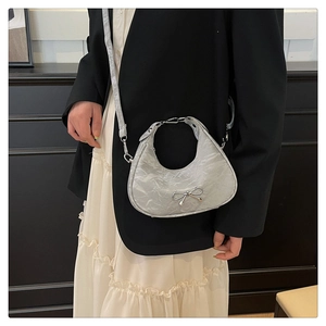 Detail of silver metallic hobo bag featuring a pleated texture and metal bow ornament