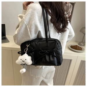 Détail d'un sac à bandoulière noir avec poches à nœuds et breloque nuage blanc sur mannequin