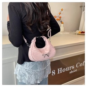 Detail of pink satin hobo bag with silver bow accent and side ruched design on shoulder strap