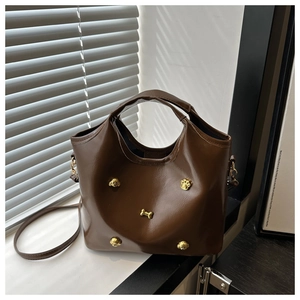 Close-up of brown handbag featuring gold puppy rivets and glossy leather texture