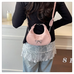 Detail of pink crescent bag featuring silver metal bow and pleated texture finish