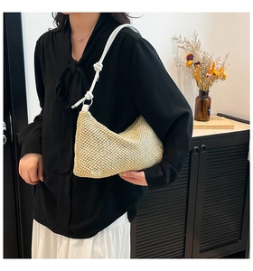 Detail of hand-woven straw tote with white leather knot strap on a female model