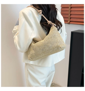 Detail of woven straw shoulder bag featuring rustic texture and stylish knot accents