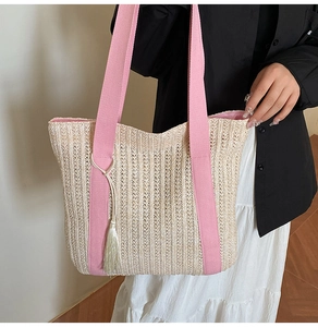 Détail du sac cabas en paille avec bandoulières roses et pendentif pompon beige clair