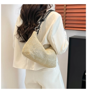 Detail of woven straw shoulder bag with black rope strap on a model for casual beach style