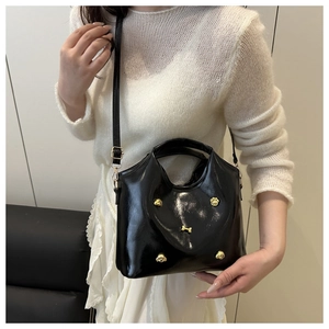 Detail of glossy black patent leather handbag with gold puppy charms and strap