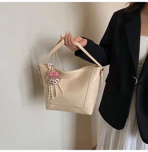Detail of cream white tote bag with textured faux leather and plush bear charm