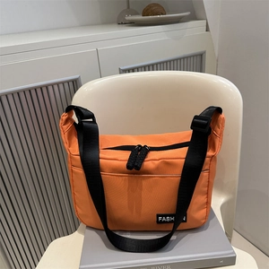 Orange large capacity nylon dumpling bag with adjustable strap on white chair display
