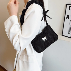 Chic black underarm bag with ruffled shoulder strap and silver butterfly accent
