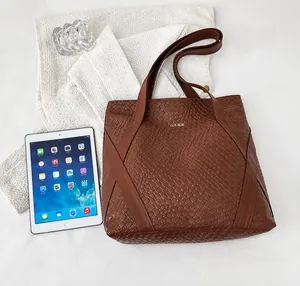 Detailed top view of large brown woven tote bag next to an iPad for size comparison