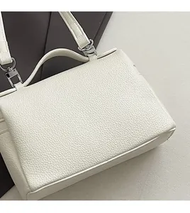 Close-up of white lychee pattern leather handbag with silver metallic buckle detail